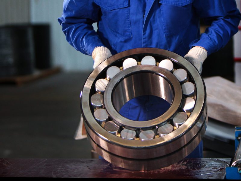 The finished bearing is in the hands of a worker at the factory. Photo without a face. Bearing production concept. Photo in the interior of the plant. The finished bearing is in the hands of a worker at the factory. Photo without a face. Bearing production concept. Photo in the interior of the plant. Portrait of a man in overalls.